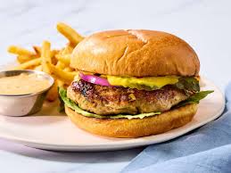 Juicy grilled turkey burger served in a bun with fresh lettuce, tomato slices, red onion, and creamy sauce